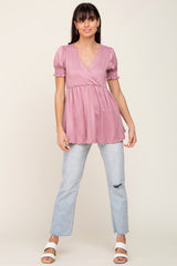 woman wearing a rose pink peplum top with puff sleeves paired with light blue distressed jeans and white sandals