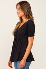 woman wearing a black short sleeve peplum top with a v-neck and smocked sleeve details
