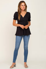 woman wearing a black puff sleeve top with a v-neck and a flared hem, paired with fitted denim jeans