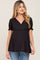 woman wearing a black short sleeve v-neck maternity top with smocked cuffs and blue jeans