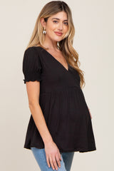 woman wearing a black maternity top with a deep v-neck and short puff sleeves, showing baby bump