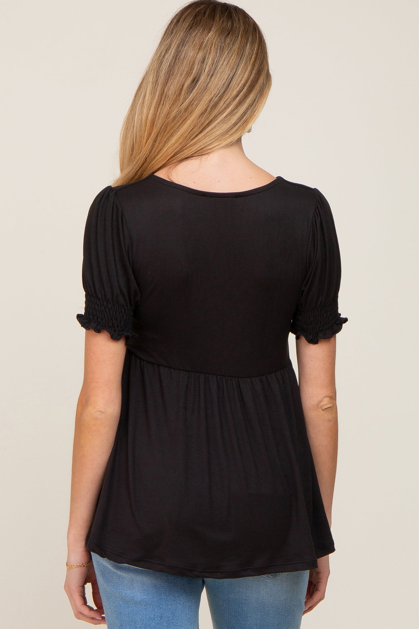 woman wearing a black maternity top with short puff sleeves and a flowy silhouette