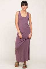 woman wearing a mauve sleeveless maxi dress and olive green sandals against a plain background