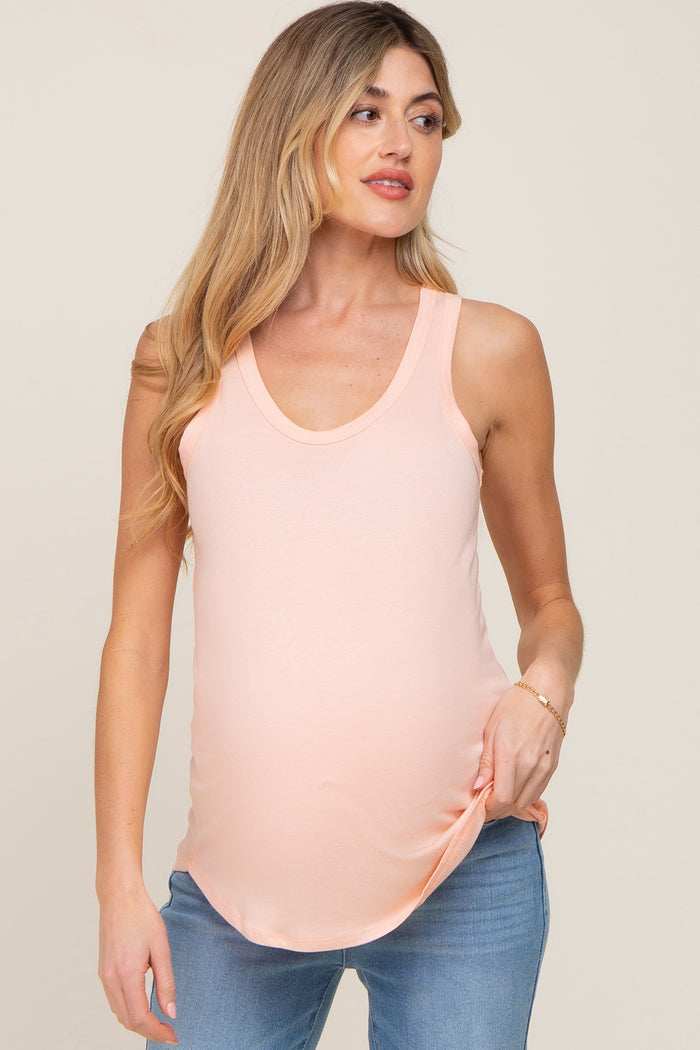 woman wearing a peach maternity tank top with a scoop neckline and a visible baby bump