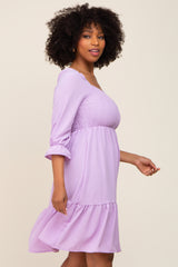 woman wearing a lavender smocked waist dress with three-quarter sleeves and a ruffled hem