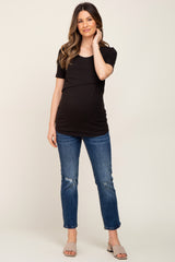 woman wearing a black short sleeve maternity top and distressed jeans, showing her baby bump