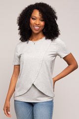 Woman wearing a grey short-sleeved nursing top with a crossover front and blue jeans
