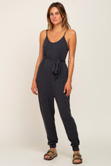 woman wearing a dark gray sleeveless jumpsuit with a tied waist and gathered cuffs on the pants