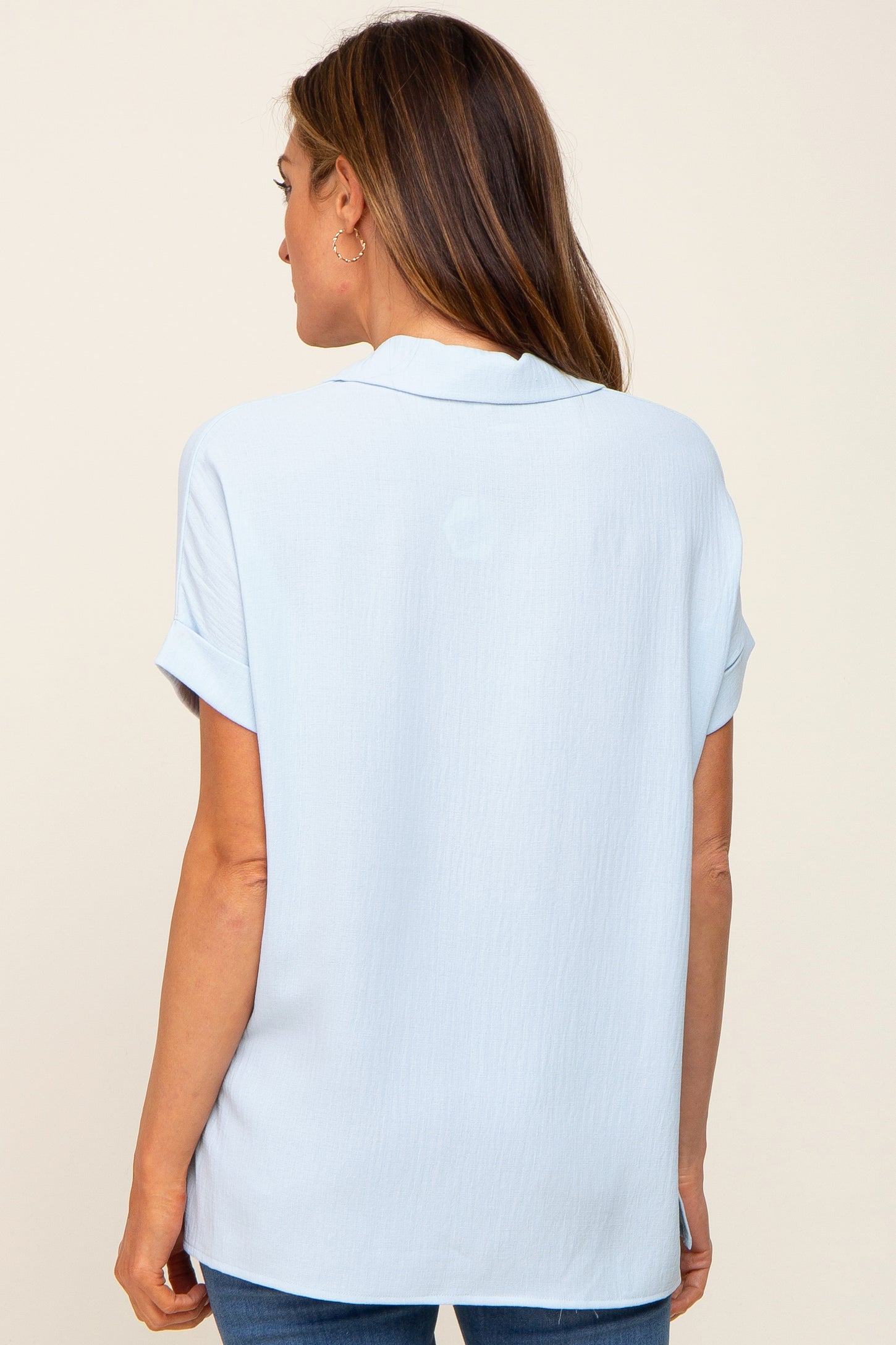 back view of a woman wearing a light blue short sleeve button down shirt with a collar