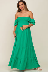 woman wearing a green off-the-shoulder maternity maxi dress with ruffle details and a visible baby bump
