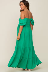woman wearing a green off-shoulder maternity maxi dress with tiered ruffle sleeves and a smocked bodice