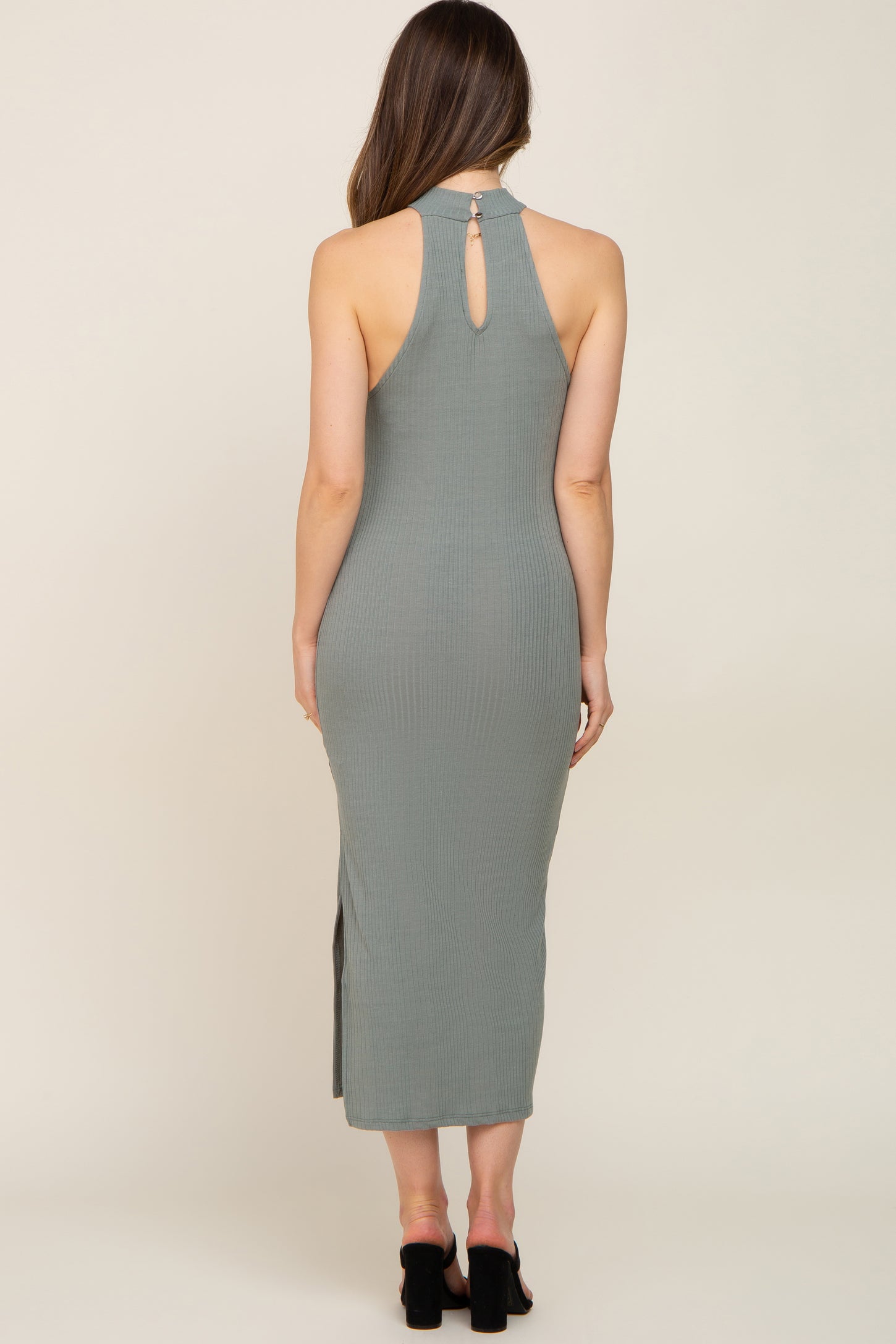 woman wearing a sage green ribbed maternity midi dress with a keyhole back and side slit