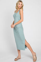 woman wearing a light green ribbed maxi dress with a side slit and adjustable straps, styled with tan sandals
