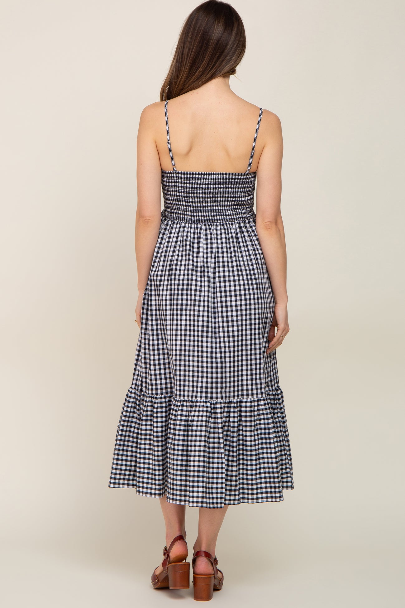 back view of woman wearing navy blue and white gingham midi dress with smocked bodice and tiered skirt