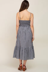 back view of woman wearing navy blue and white gingham midi dress with smocked bodice and tiered skirt