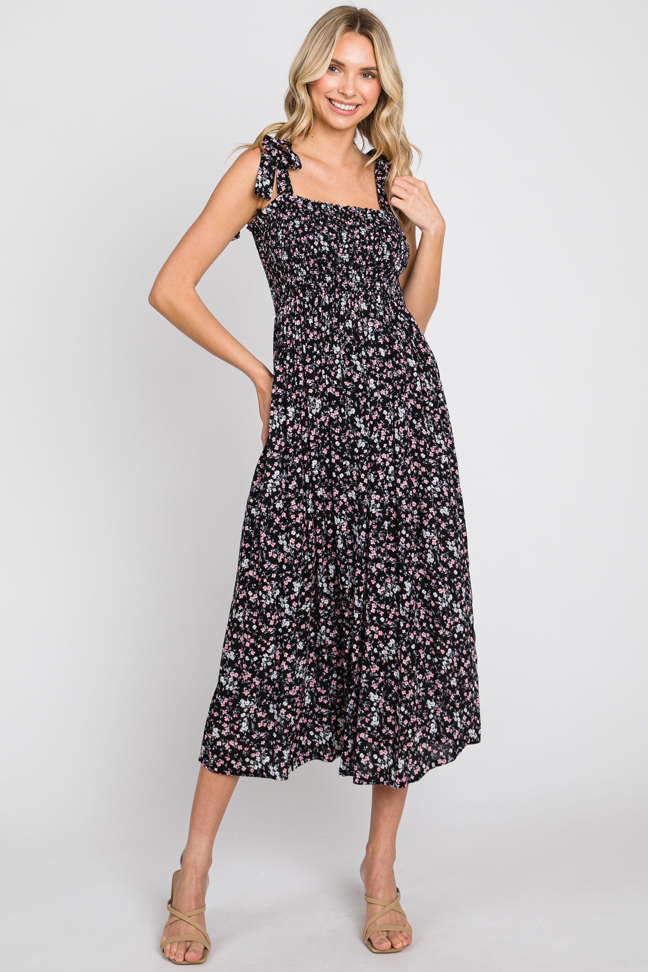 woman wearing a black floral print midi dress with tie straps and a smocked bodice