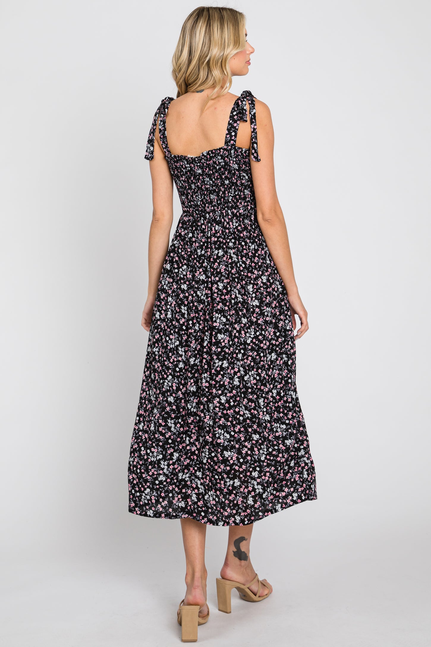 woman wearing a black floral maxi dress with smocked bodice and tie straps, shown from the back