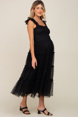 Pregnant woman wearing a black smocked maternity midi dress with ruffled straps and tiered tulle skirt