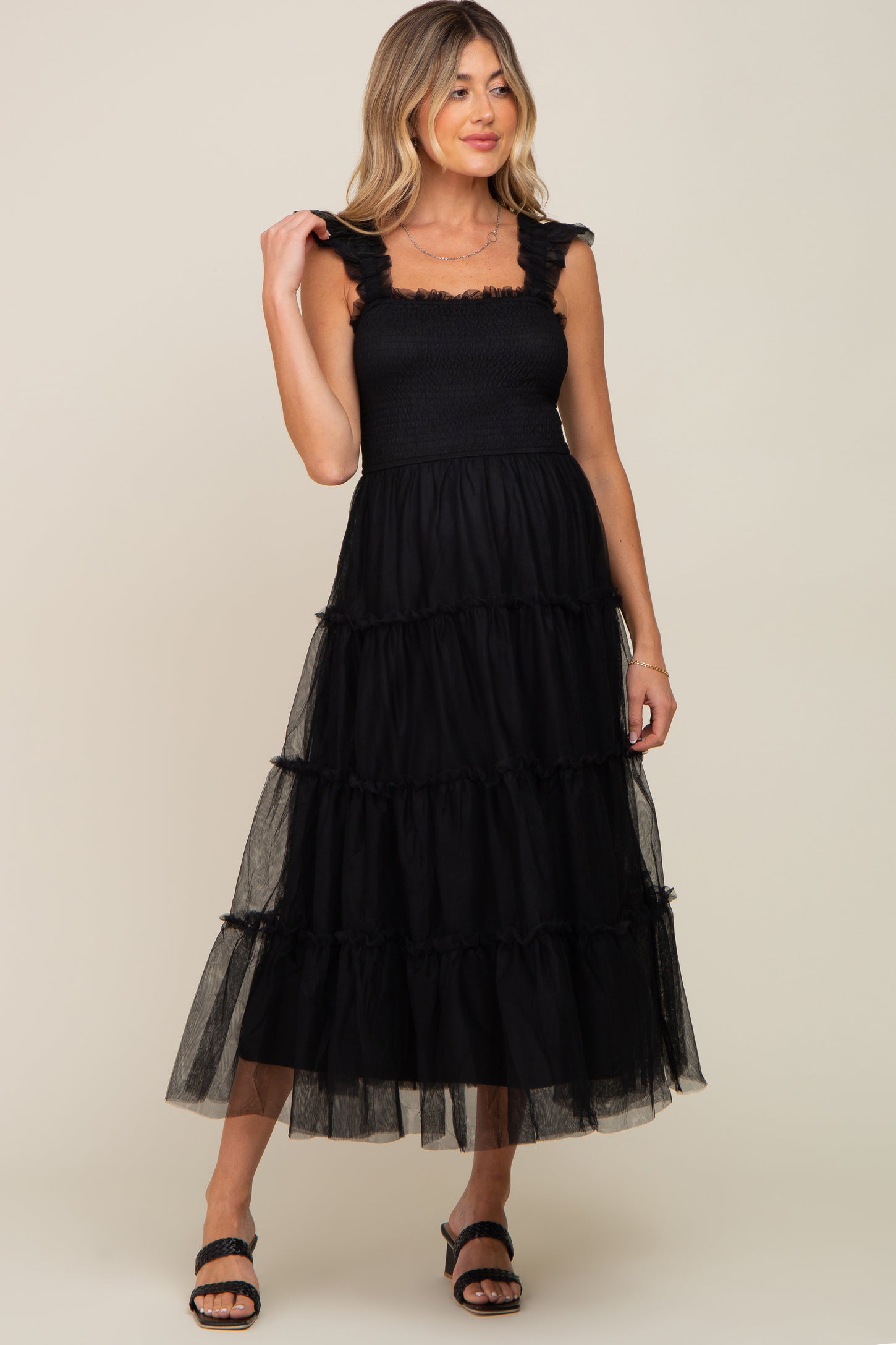 woman wearing a black maternity dress with tiered tulle layers and ruffled straps