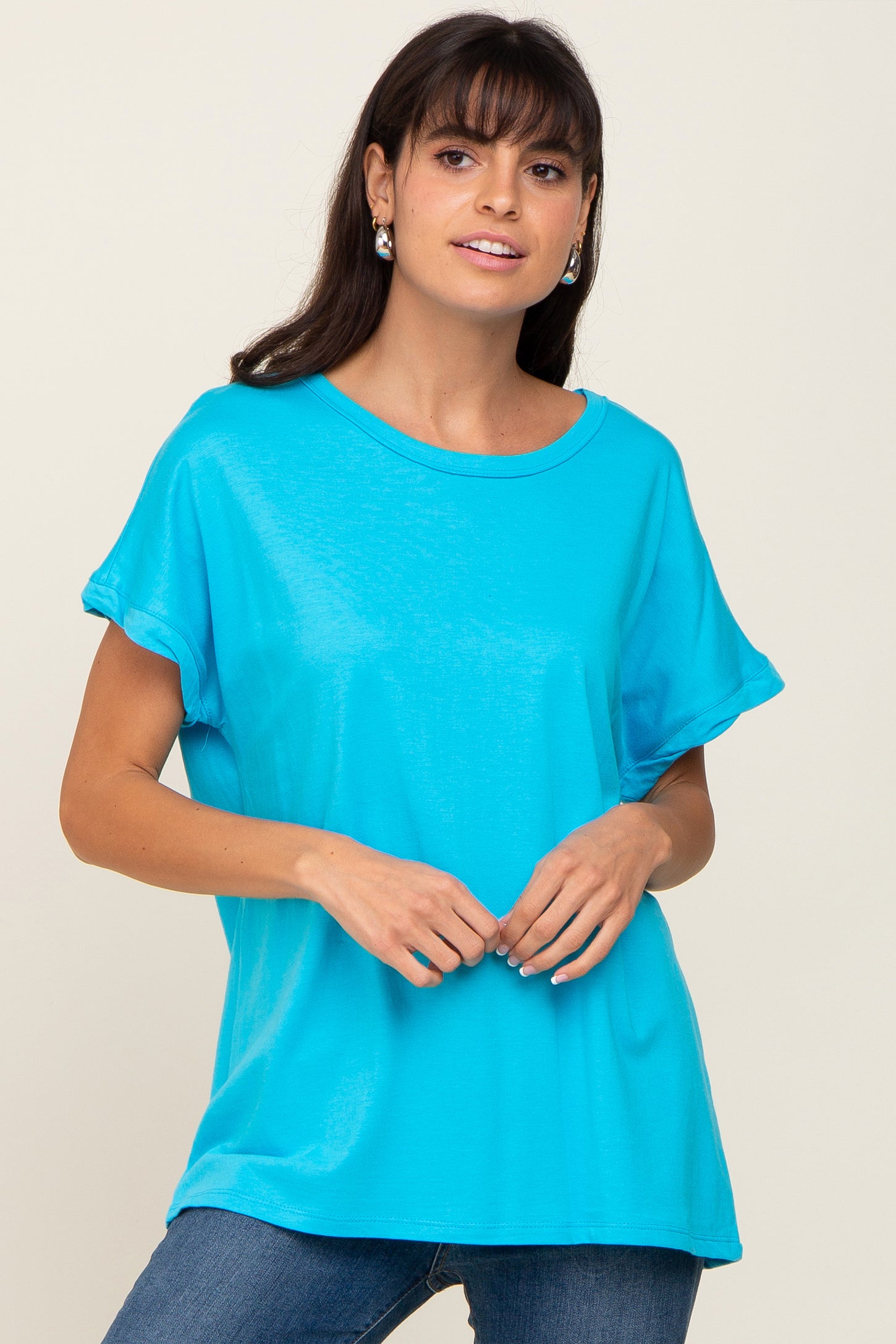 woman wearing a bright turquoise short sleeve t-shirt paired with blue jeans