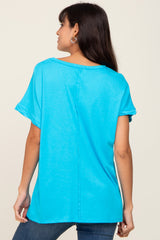 woman wearing a bright turquoise short sleeve top with rolled sleeves and a relaxed fit