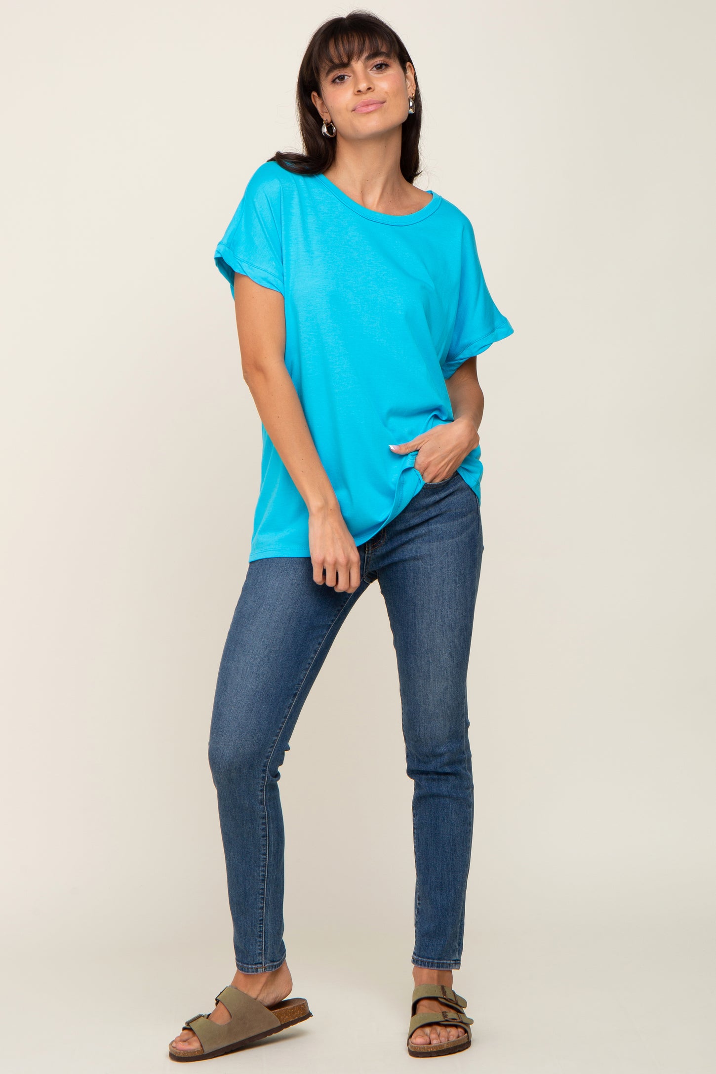 woman wearing a bright blue short sleeve top with a relaxed fit and dark skinny jeans