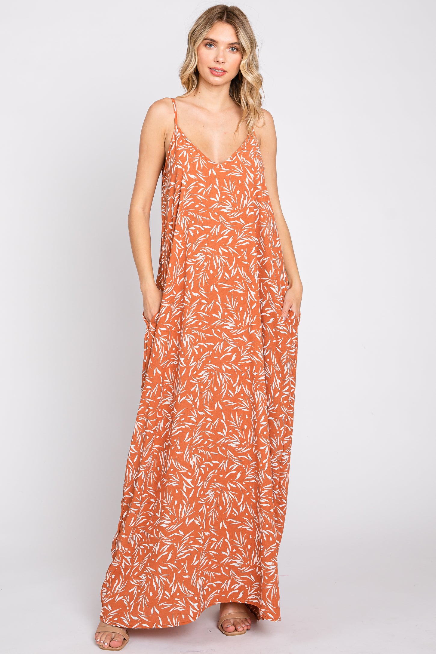 woman wearing an orange floral maxi dress with thin straps and a relaxed fit