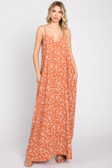 woman wearing an orange floral maxi dress with thin straps and a relaxed fit