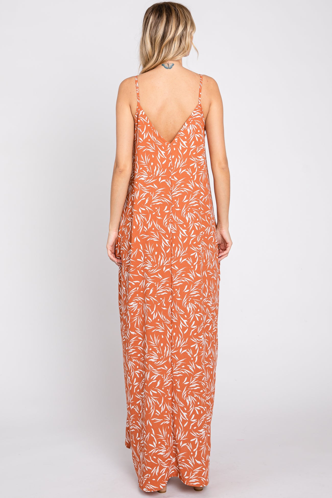 woman wearing a rust orange floral maxi dress with a low back and thin straps