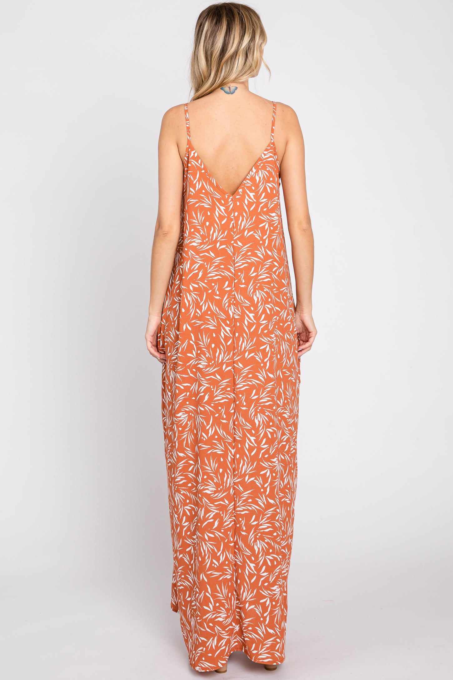 woman wearing a rust orange floral maxi dress with a low back and thin straps