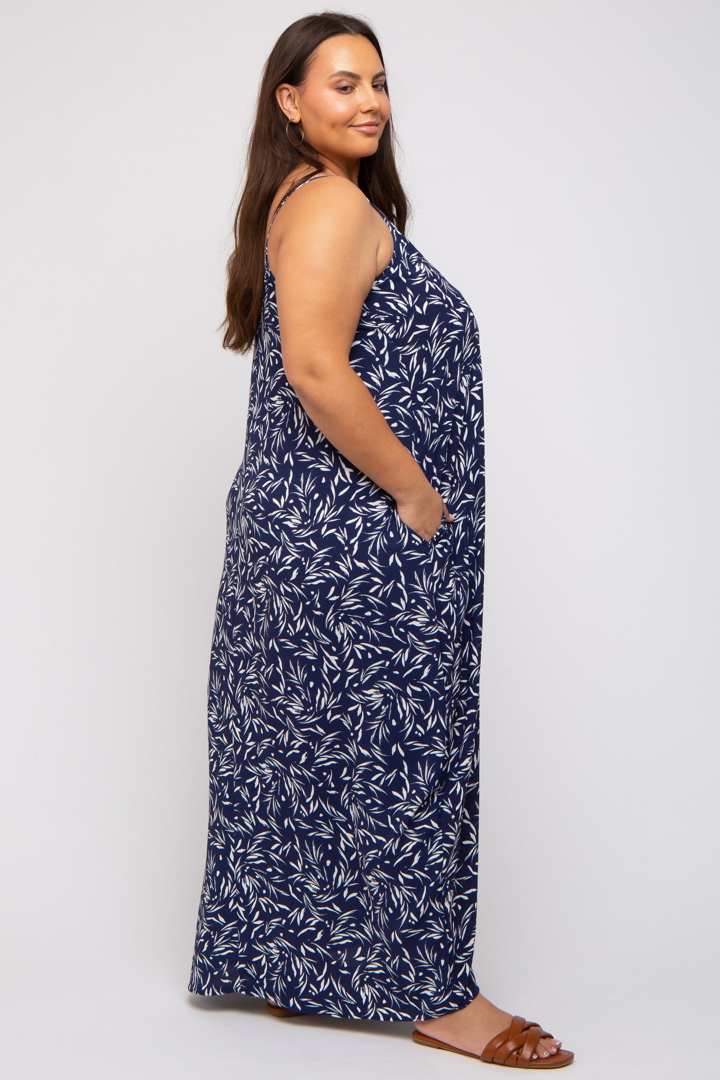 woman wearing a navy blue floral print maxi dress with pockets and sandals, shown from the side