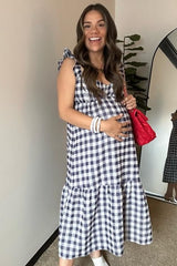 Smiling pregnant woman wearing a navy blue and white gingham maternity midi dress and holding a red quilted purse