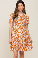 woman wearing an orange floral maternity dress with short sleeves and a tiered skirt, showing her baby bump