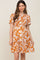 woman wearing an orange floral maternity dress with short sleeves and a tiered skirt, showing her baby bump
