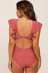 woman wearing a dusty rose maternity one-piece swimsuit with ruffled sleeves and open back design
