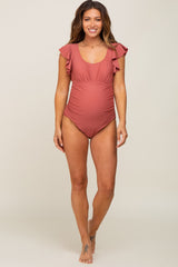 woman wearing a dusty rose maternity swimsuit with ruffle sleeves and a visible baby bump
