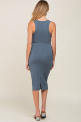 woman wearing a slate blue midi maternity dress with a fitted silhouette and a back slit