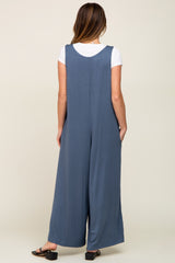 woman wearing a blue sleeveless jumpsuit with wide legs, viewed from the back