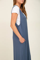 woman wearing a gray sleeveless maxi dress with pockets over a white t-shirt
