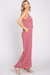 woman wearing a light pink floral maxi dress with a tie front and pockets, posed sideways