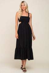 woman wearing a black sleeveless midi dress with side cutouts and a tiered hem