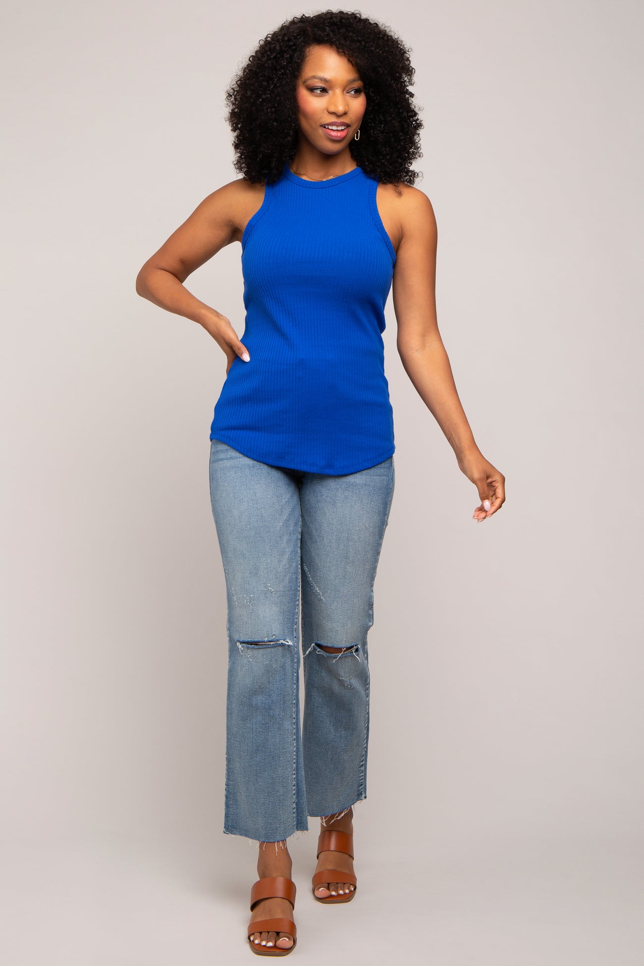 woman wearing a bright blue ribbed tank top and distressed light wash jeans with heeled sandals