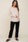 woman wearing a light pink long sleeve maternity top and black pants, holding her baby bump