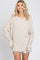 woman wearing a beige long sleeve oversized top with rolled cuffs and distressed denim shorts