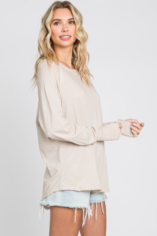 woman wearing a beige long sleeve top with thumbholes and pairing it with light blue distressed shorts