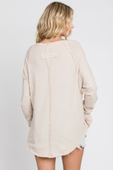 woman wearing a beige long sleeve top with a round hem and seam detailing on the back