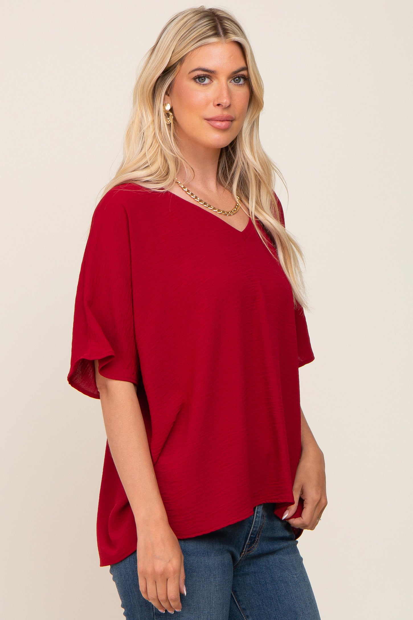 woman wearing a red short sleeve v-neck top with a relaxed fit and layered sleeves