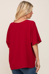 woman wearing a red oversized top with short sleeves and a relaxed fit, seen from the back