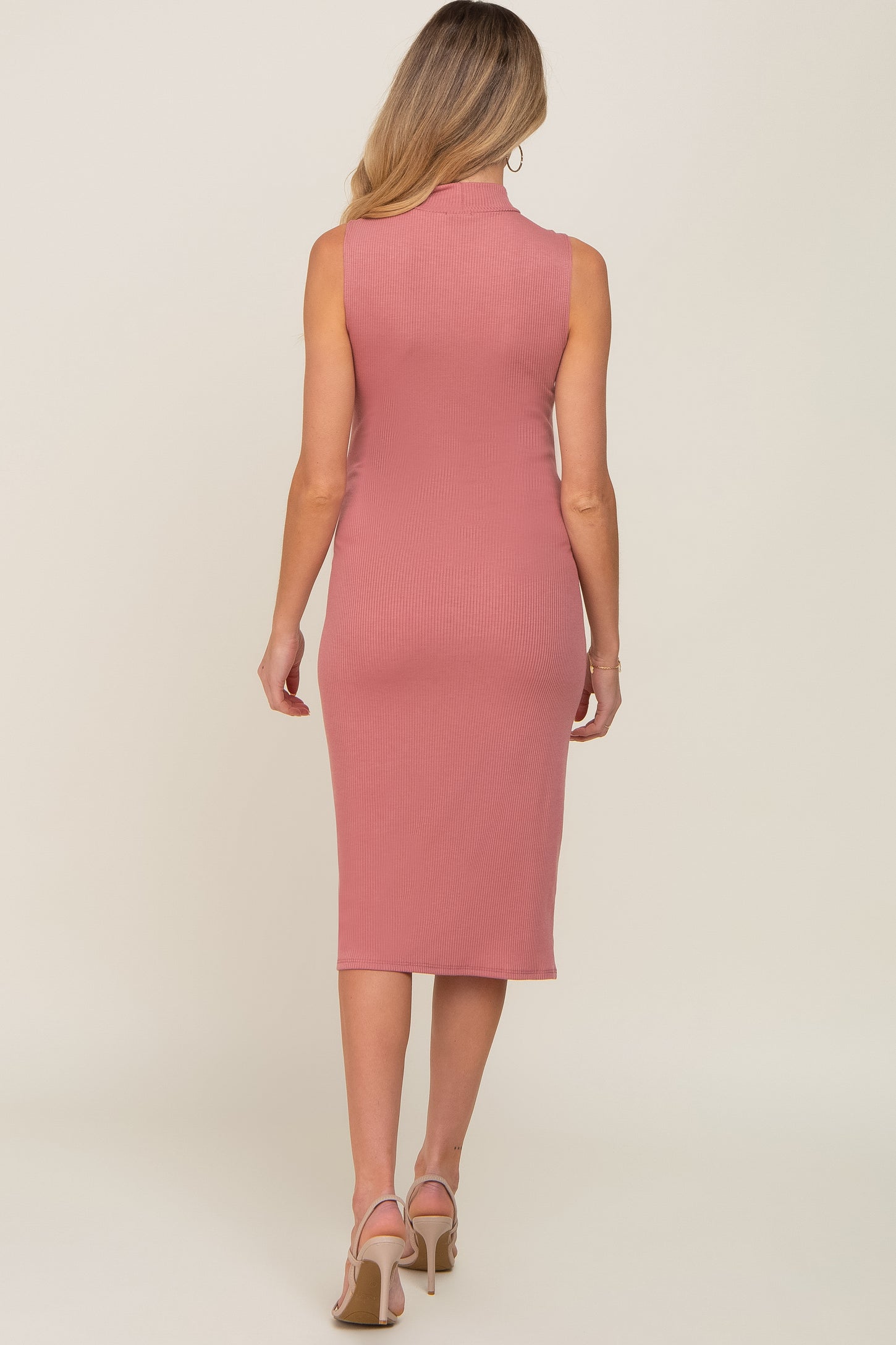 Back view of a woman wearing a mauve ribbed sleeveless midi dress with a mock neck and beige heels