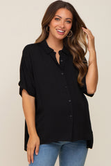 smiling woman wearing a black short sleeve button down maternity top and blue jeans